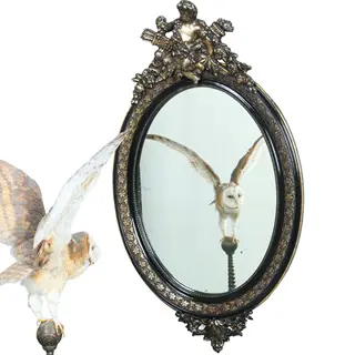 Ovale spiegel in zwart met zilver bekroond door cupido met pijlen en toorts