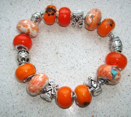 Armband in oranje met bedels - maat naar wens
