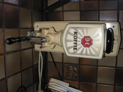 Douwe egberts wandkoffiemolen met glazen opvangbakje.