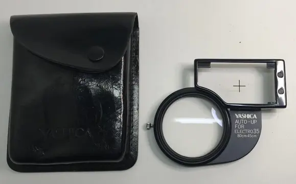 4 x Yashica items: an angle viewfinder; a viewing and taking lens no. 1; an Electro35 close-up attachment and an extension bellows 35mm SLR camera.